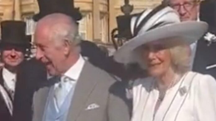 News Update: As King Charles engages in conversation with guests during the Buckingham Palace garden party, Queen Camilla seems to be encouraging him along.